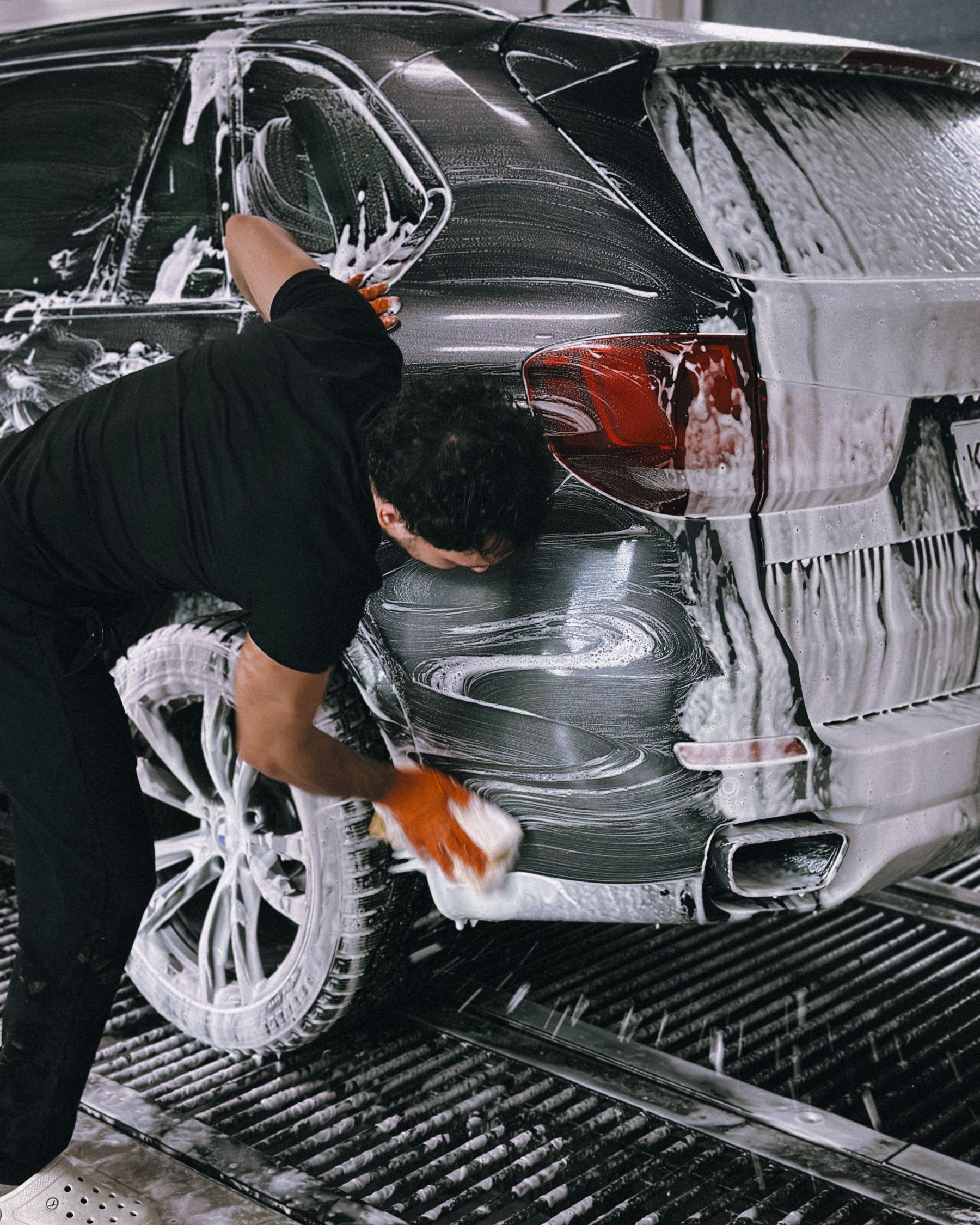 A dark car covered with wash foam